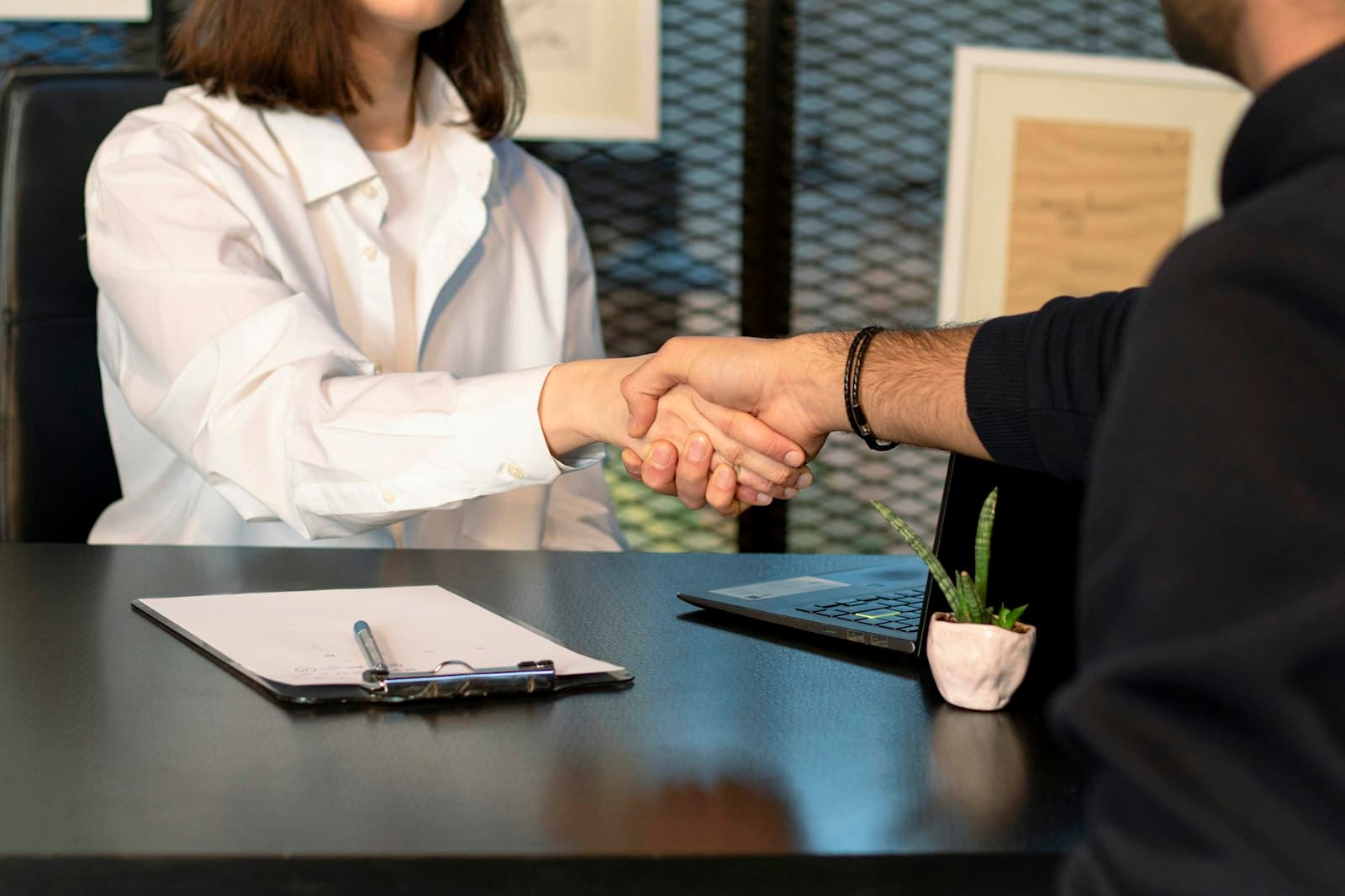 Productor de seguros cerrando un acuerdo con un cliente frente a una notebook